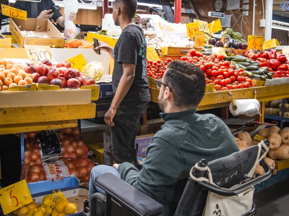 Support worker helping a participant in a wheelchair select fresh market produce